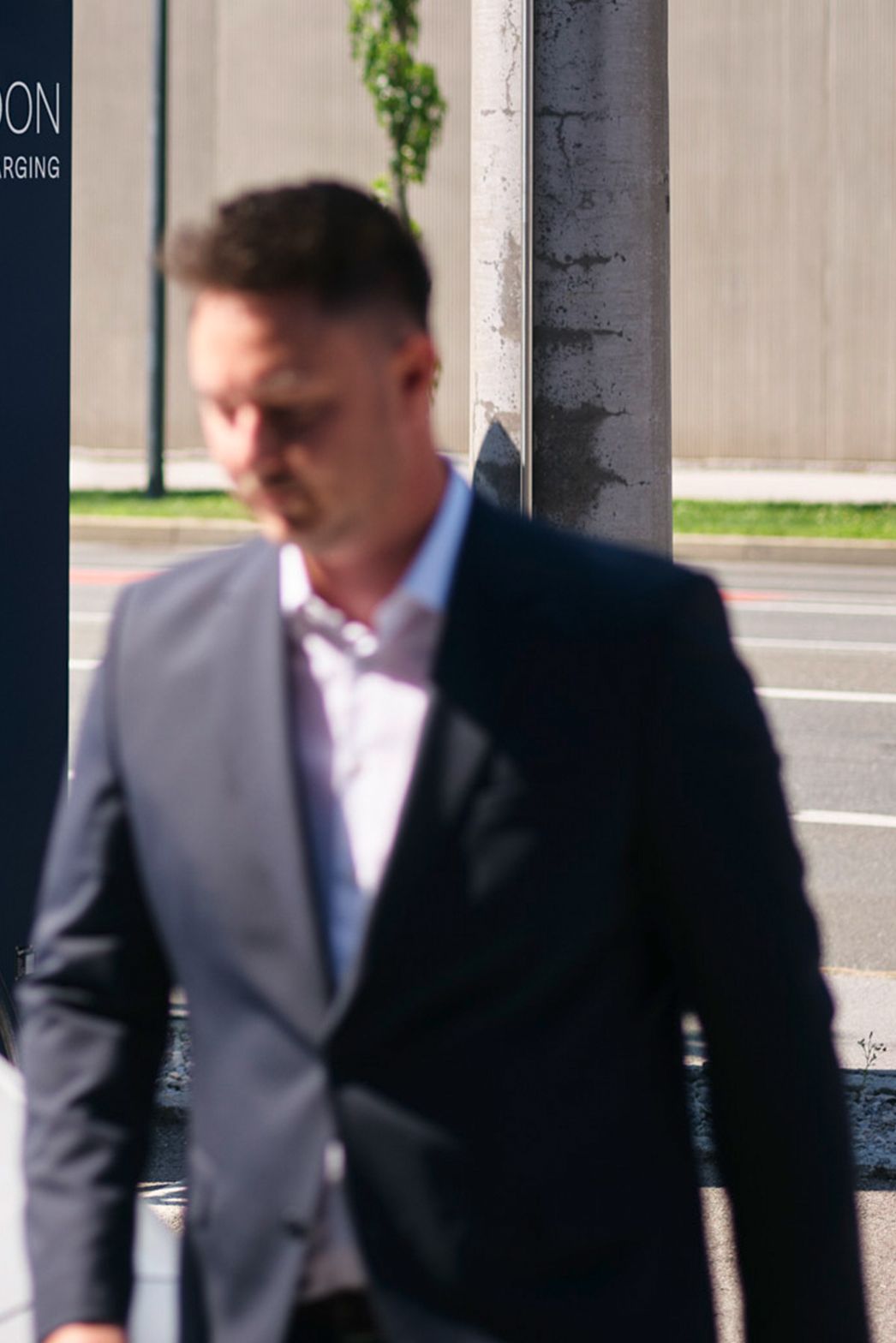Man walks in front of a car in front of a charging station