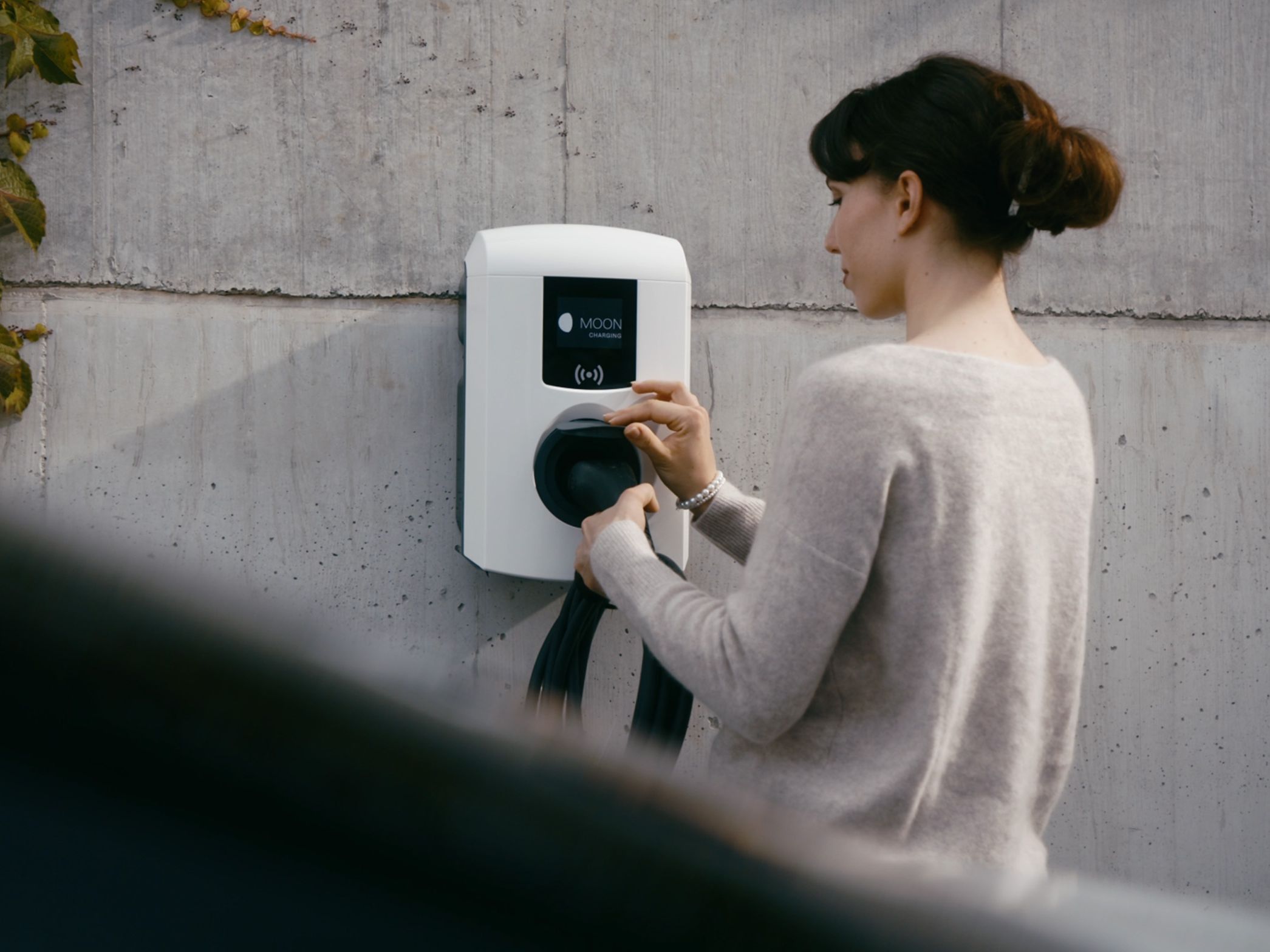 Person plugs cable into wallbox