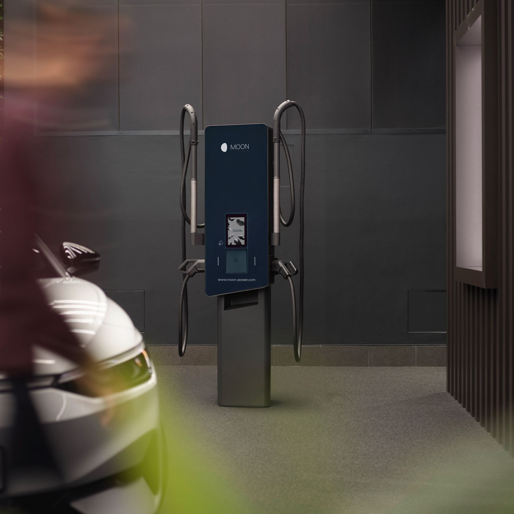 Wallbox in front of a gray wall with electric car in the foreground