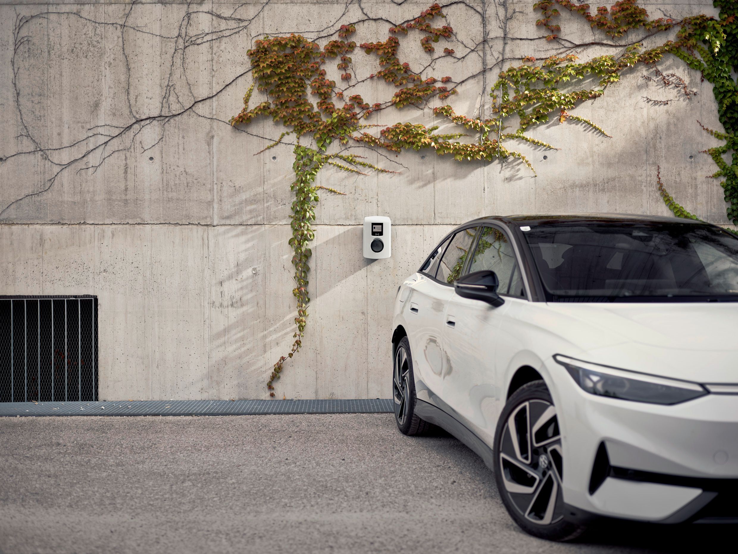 Electric car stands in front of a concrete wall with wallbox