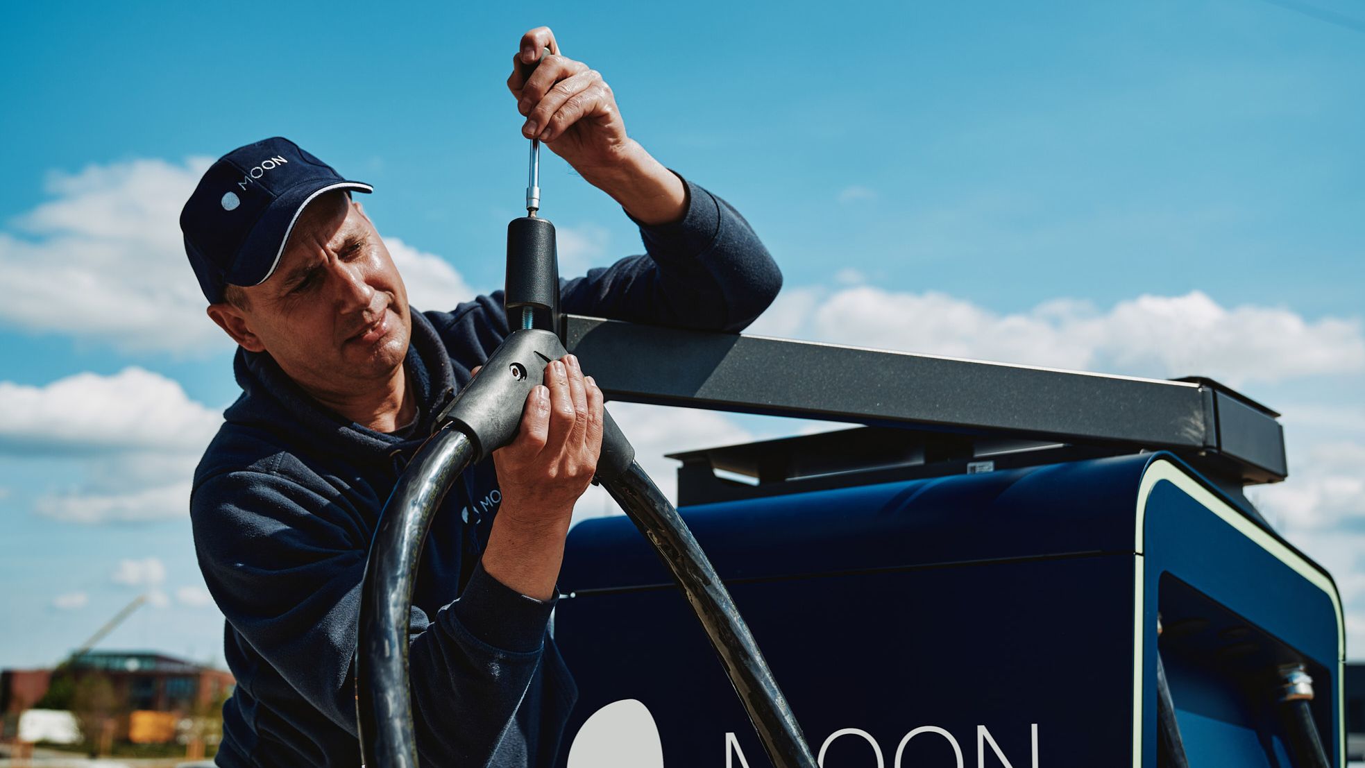 a man screws on the POWER Charger fast charging station