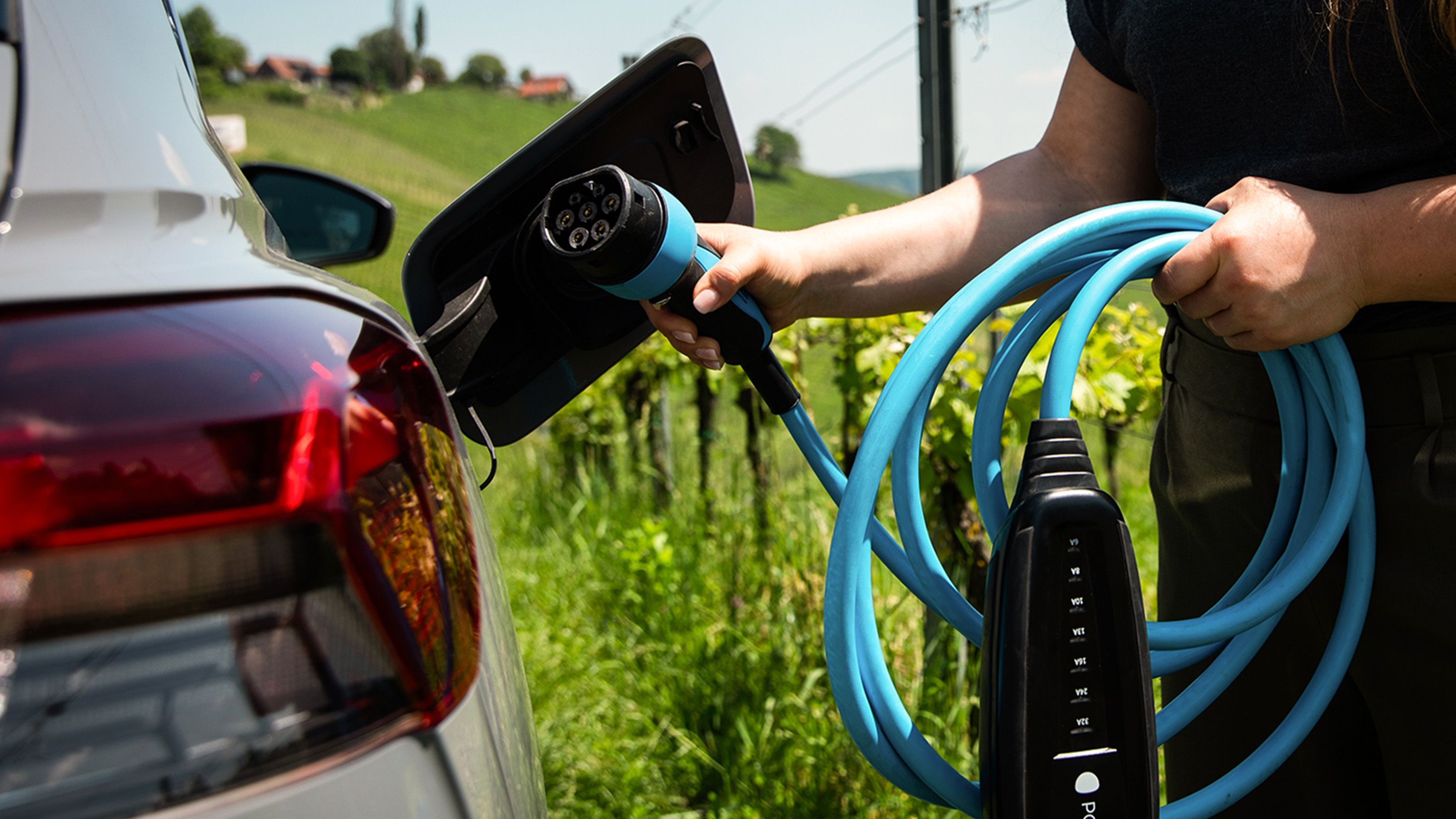 Person holding a POWER2Go cable in their hands and putting it in a car