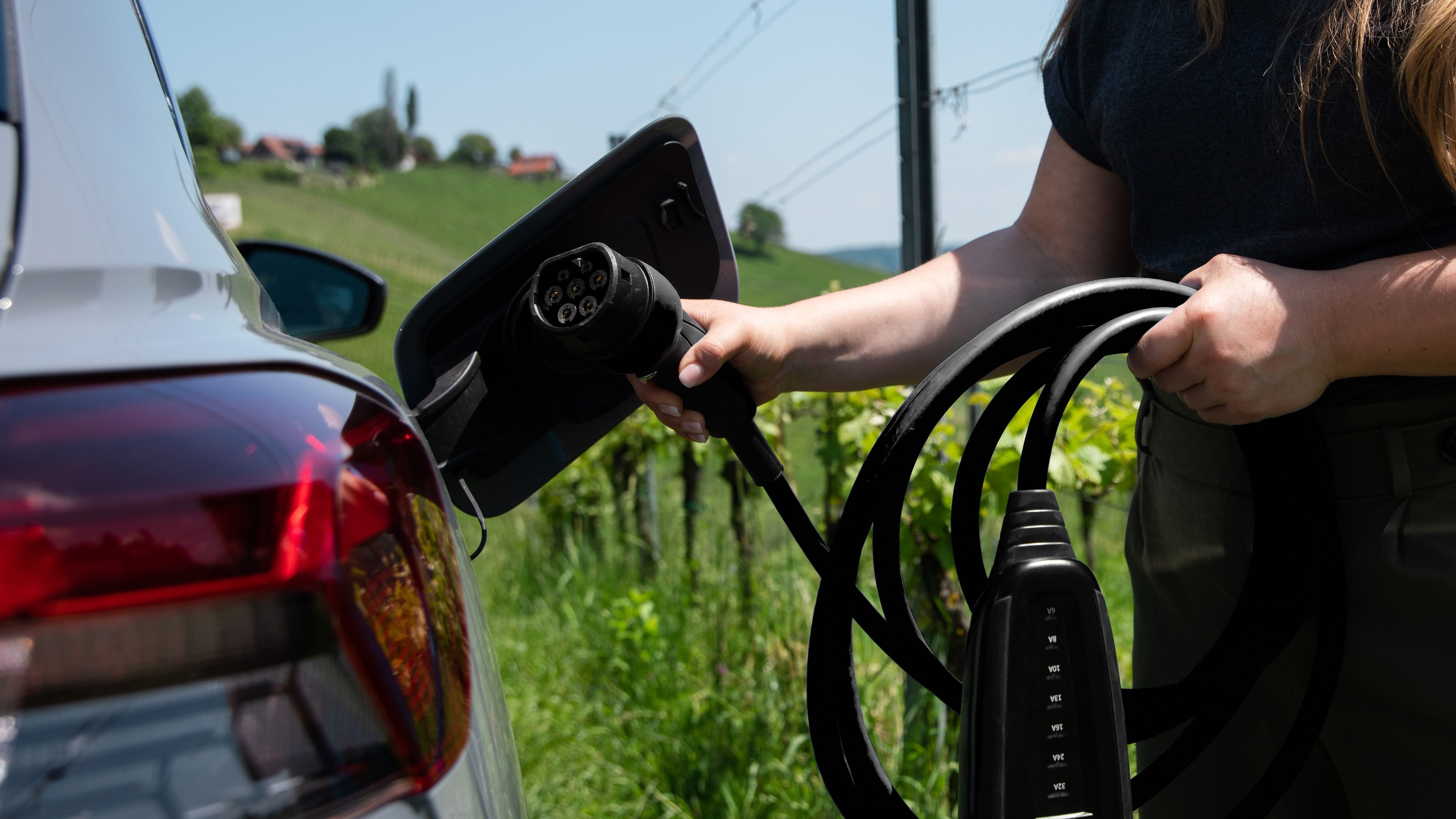 Person holding a POWER2Go cable in their hands and putting it in an electric car