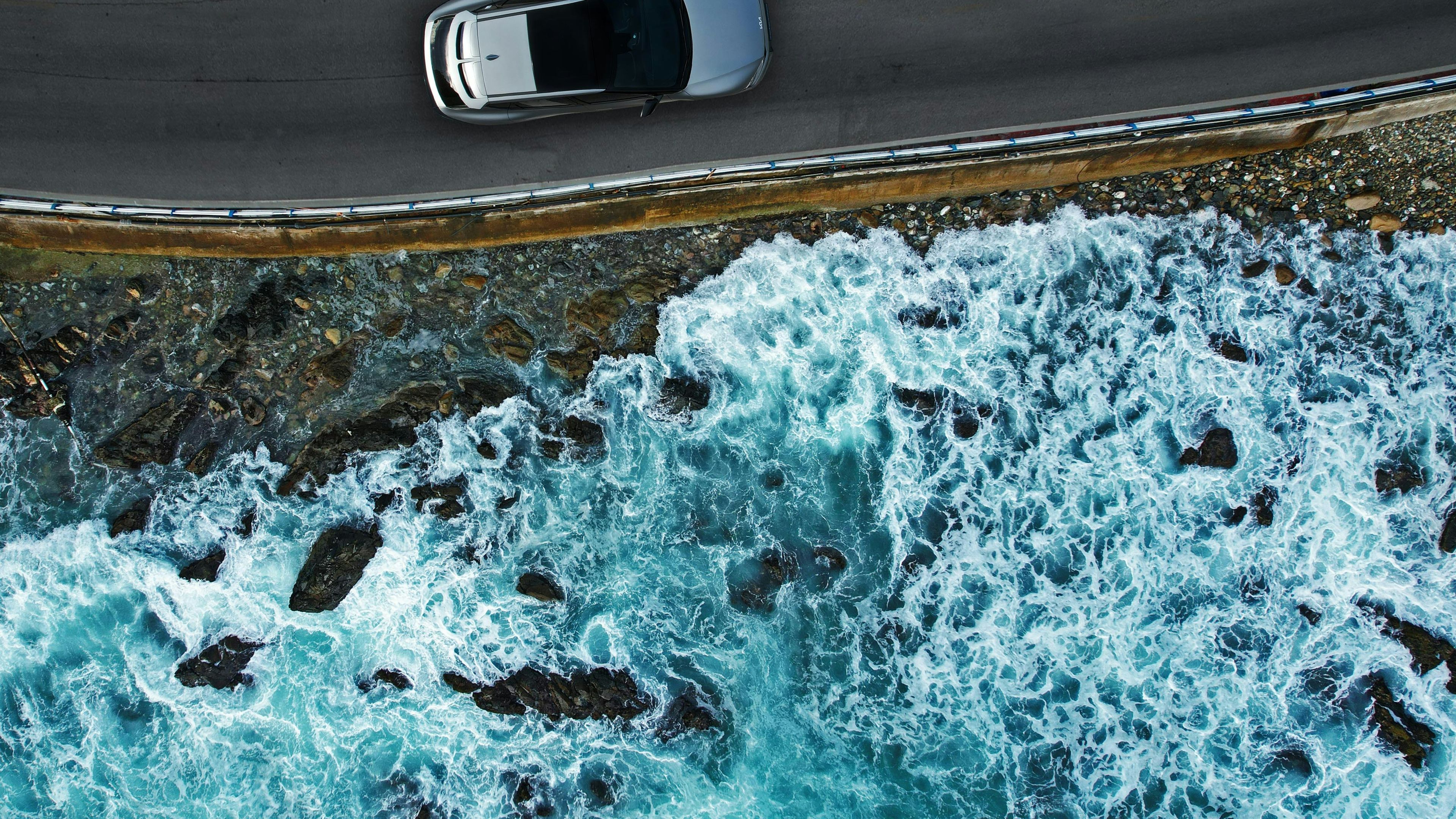 Aerial view of a car driving along the sea 