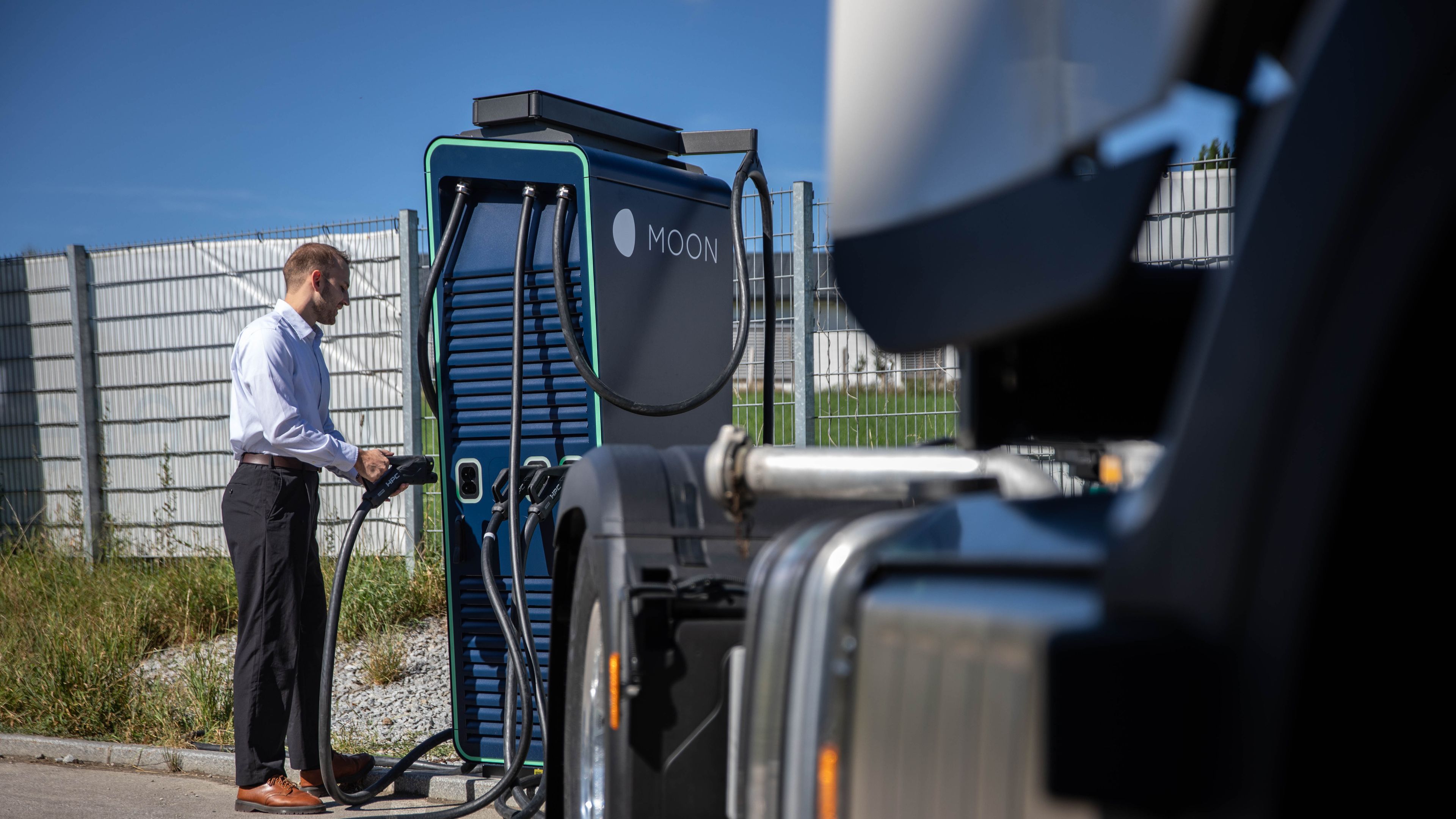 A man takes the plug of a HYC 200-400 fast charging station behind a truck