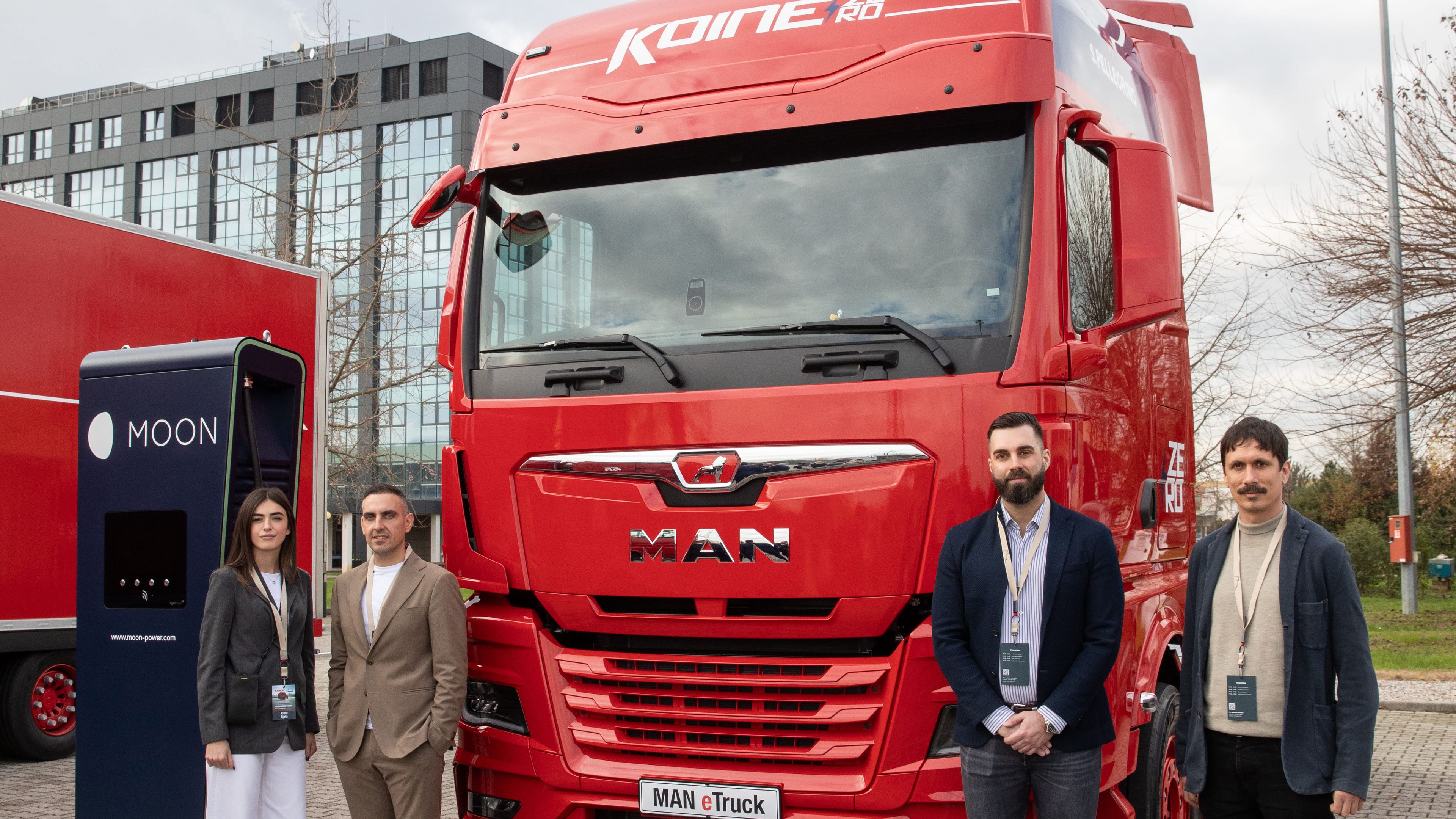 four people standing next to a POWER Charger HYC 400 and a Koiné truck