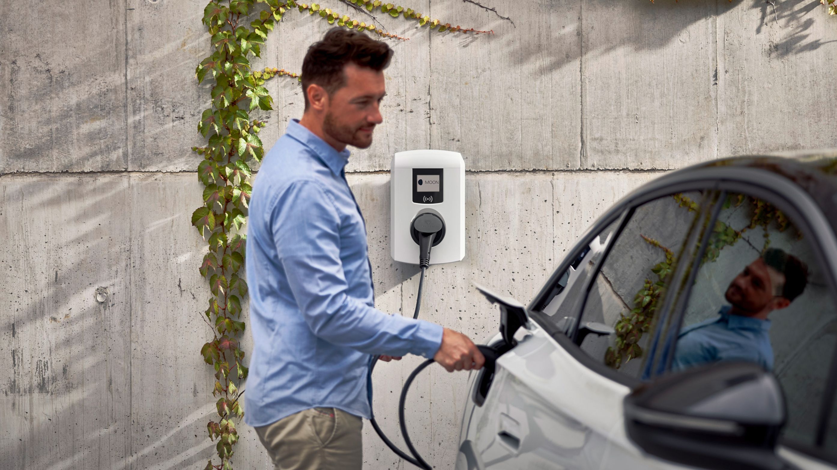 Man sticks tap valve of a wallbox into an electric car