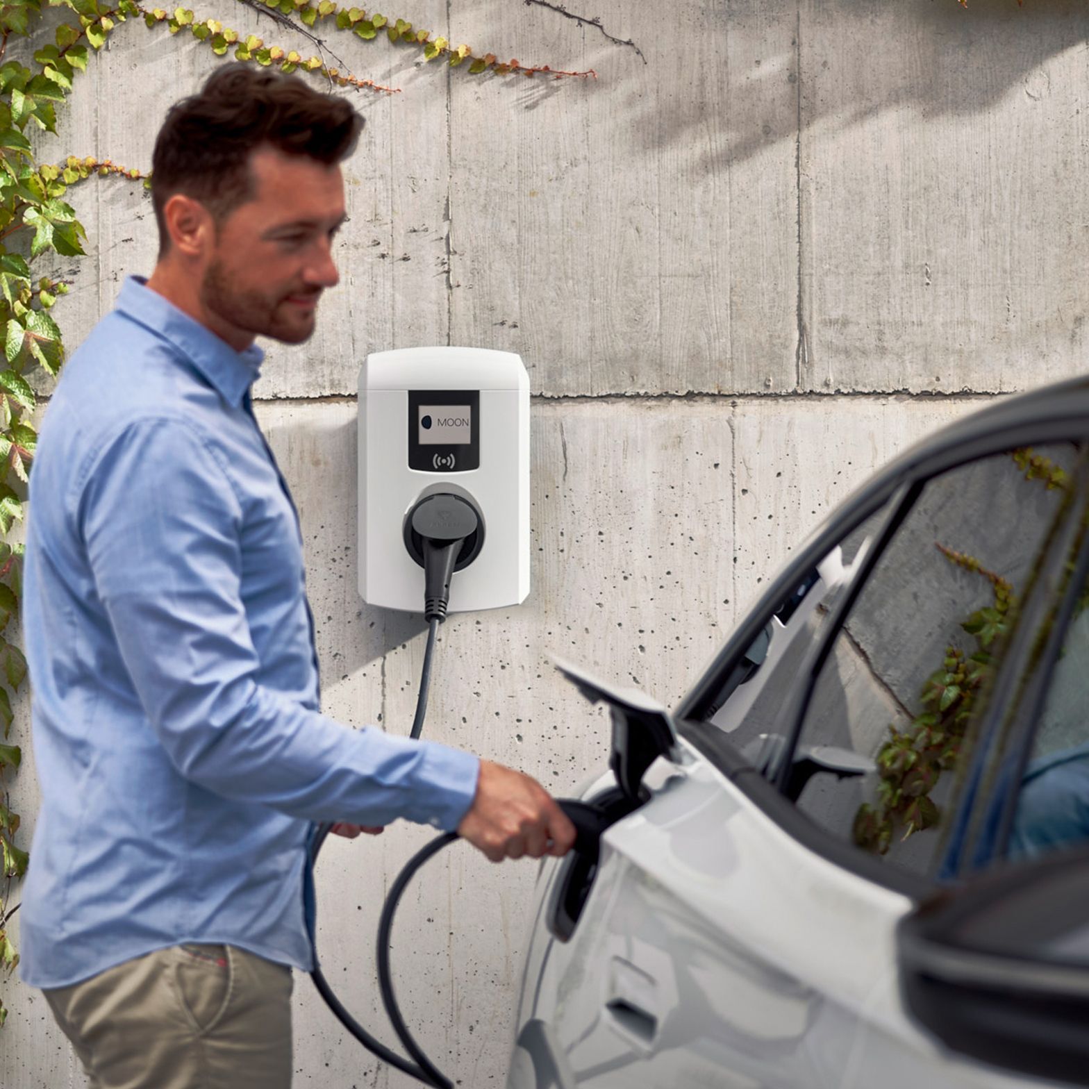 Man sticks tap valve of a wallbox into an electric car