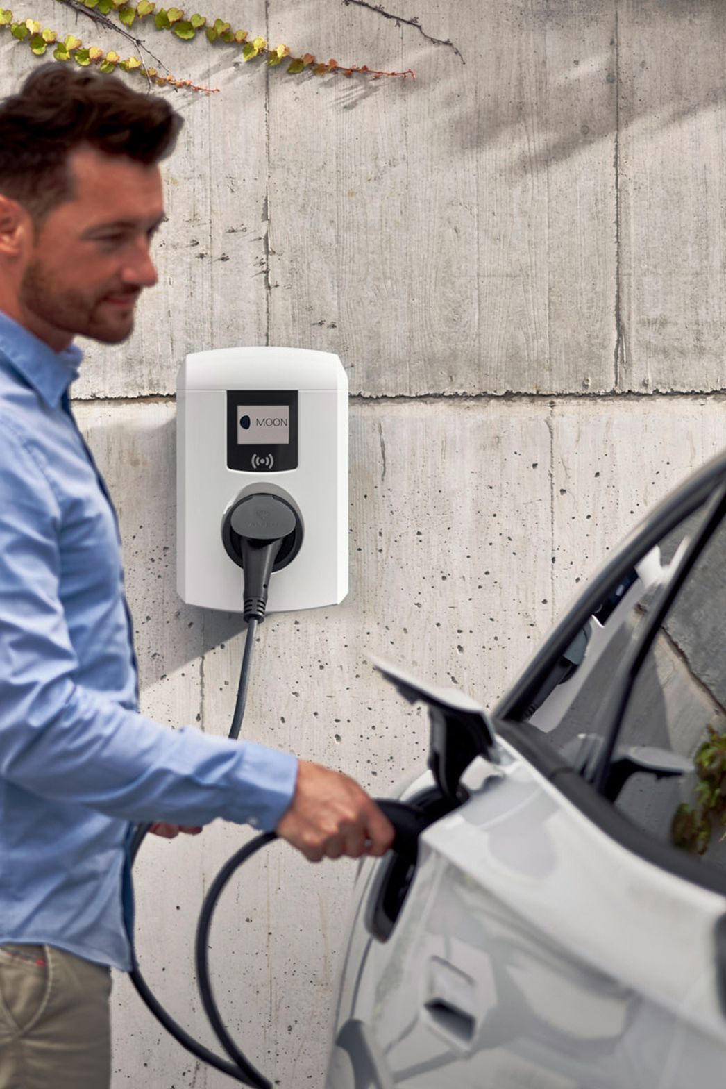 Man sticks tap valve of a wallbox into an electric car