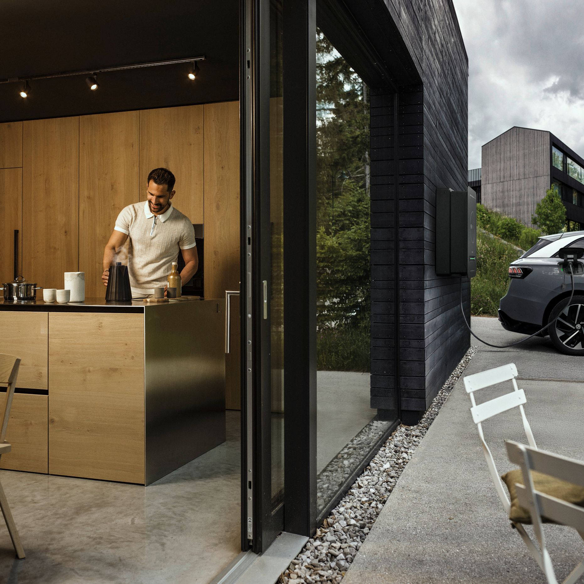 Man in kitchen while car powered by bidirectional wallbox house
