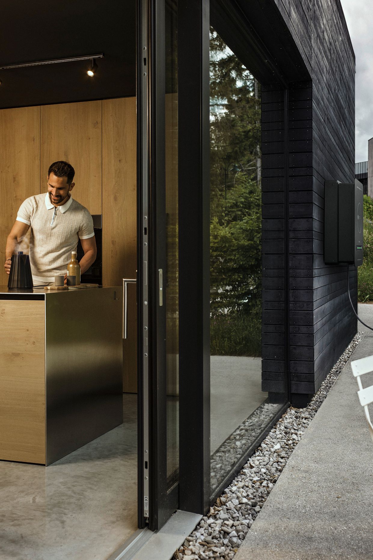 Man in kitchen while car powered by bidirectional wallbox house