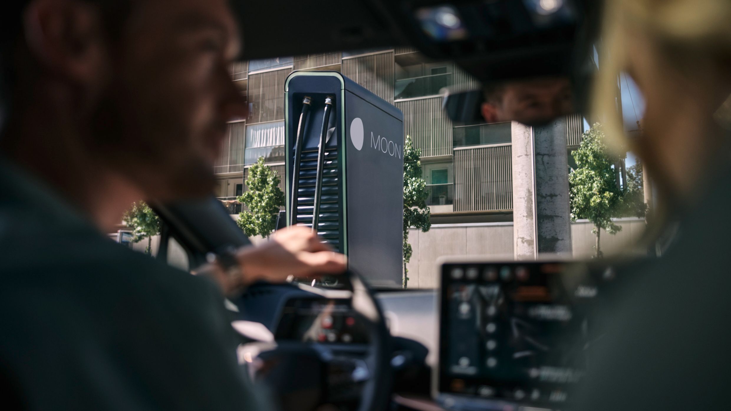 two people in a car in front of a fast charging station