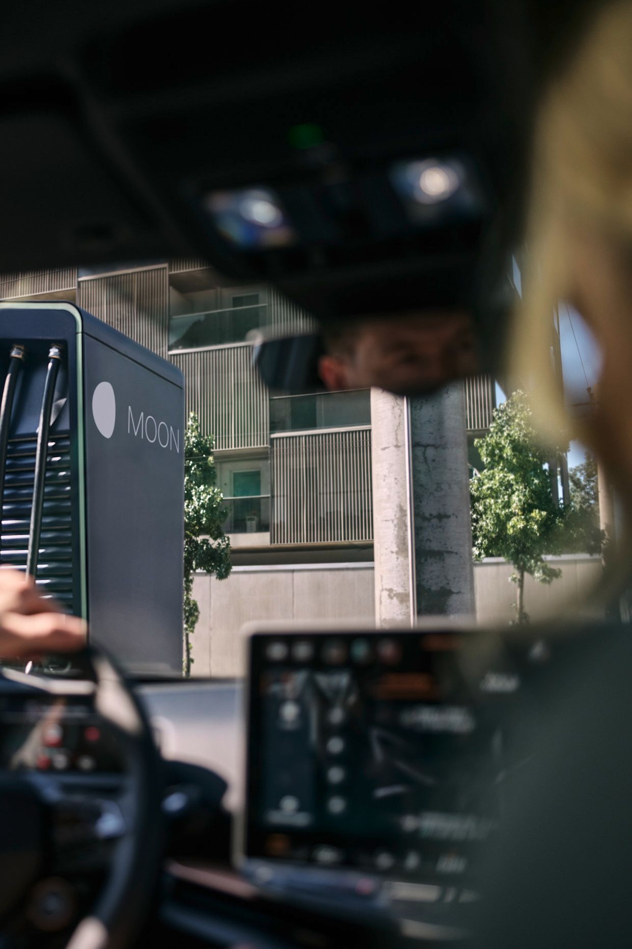 two people in a car in front of a fast charging station
