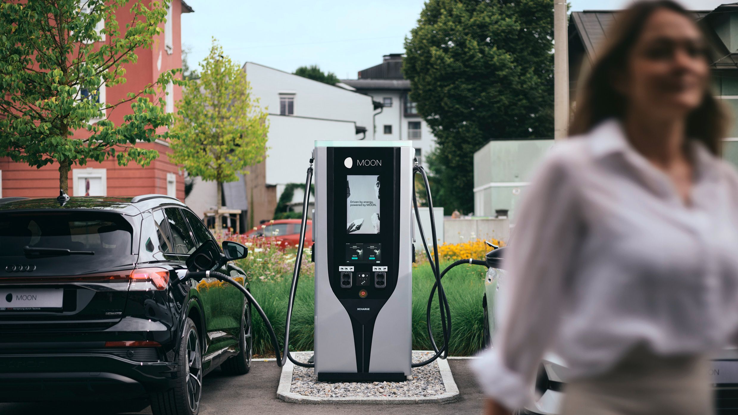 Person geht von Schnellladestation zwischen zwei E-Autos weg