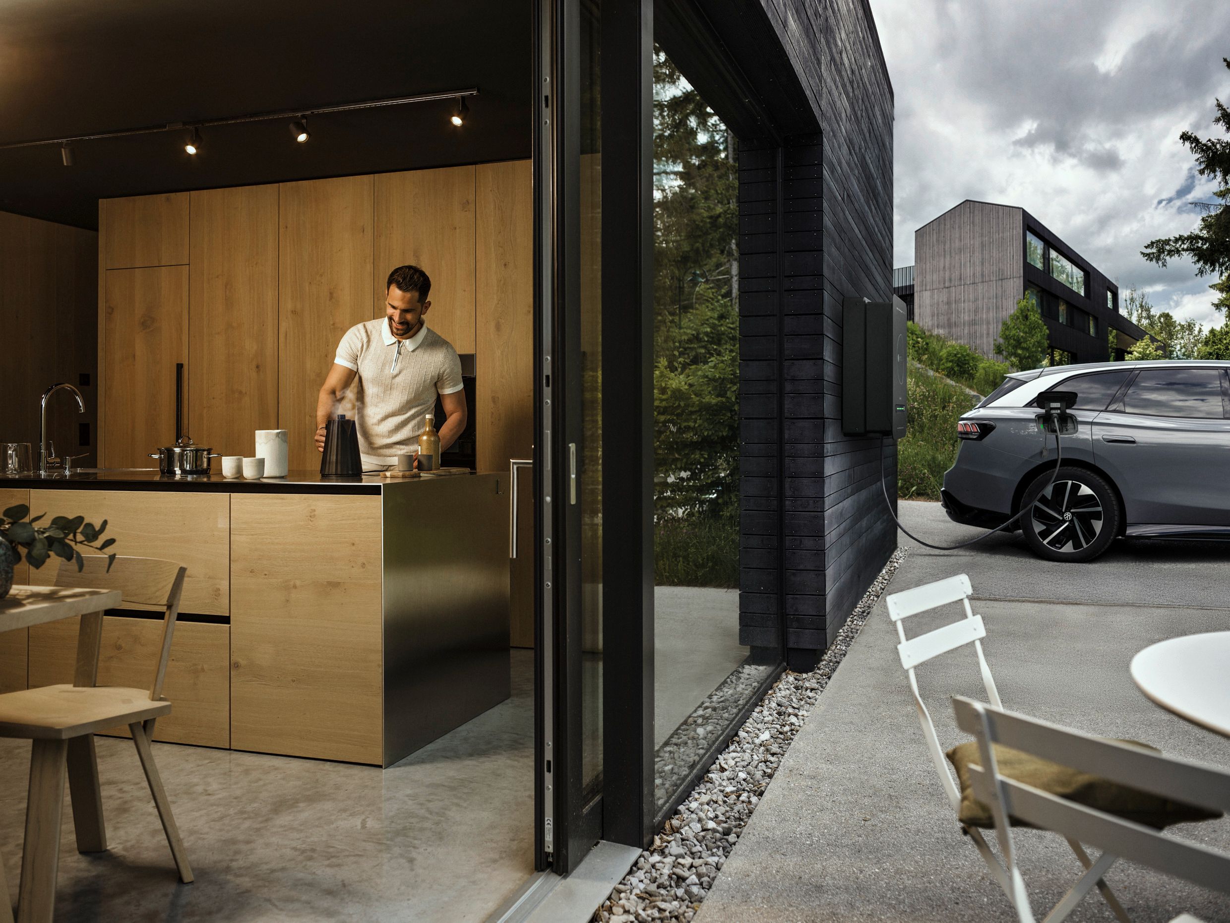Mann in der Küche während Auto durch bidirektionale Wallbox Haus mit Strom versorgt