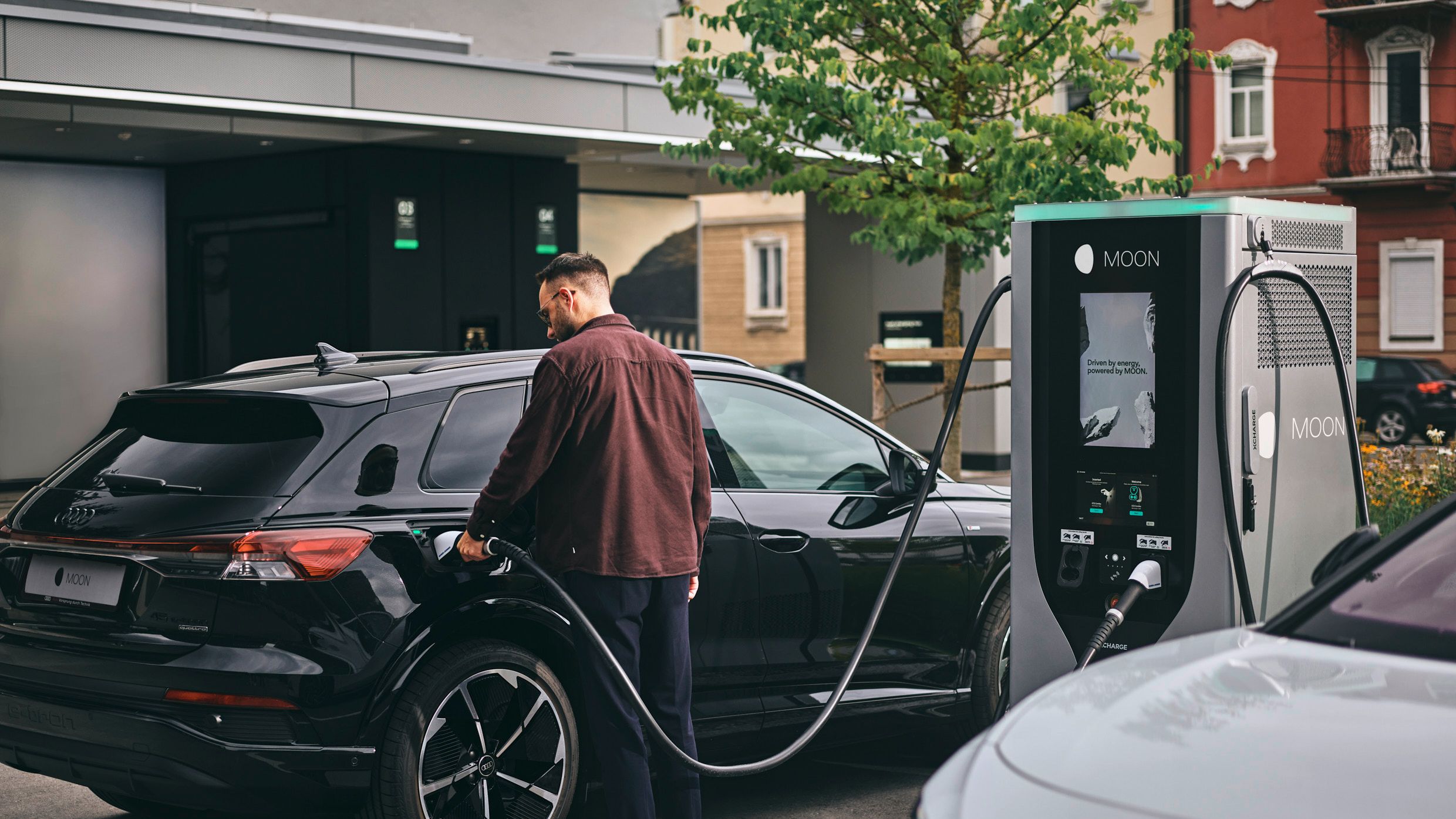 Person charging electric car at a fast charging station