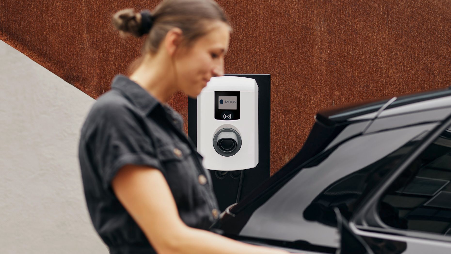Woman sticking tap valve from a wallbox into a car