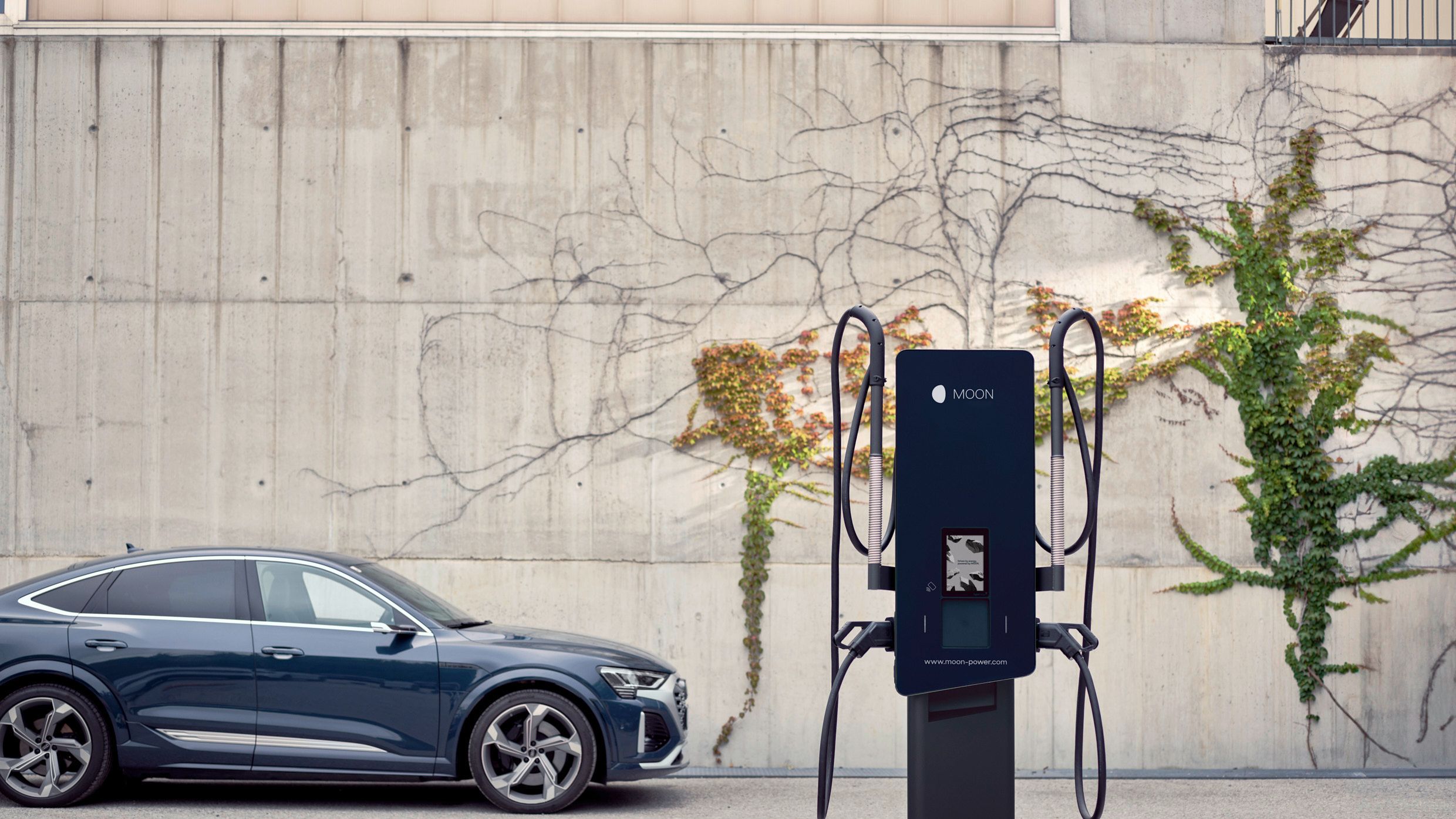 Wallbox and electric car in front of an overgrown wall