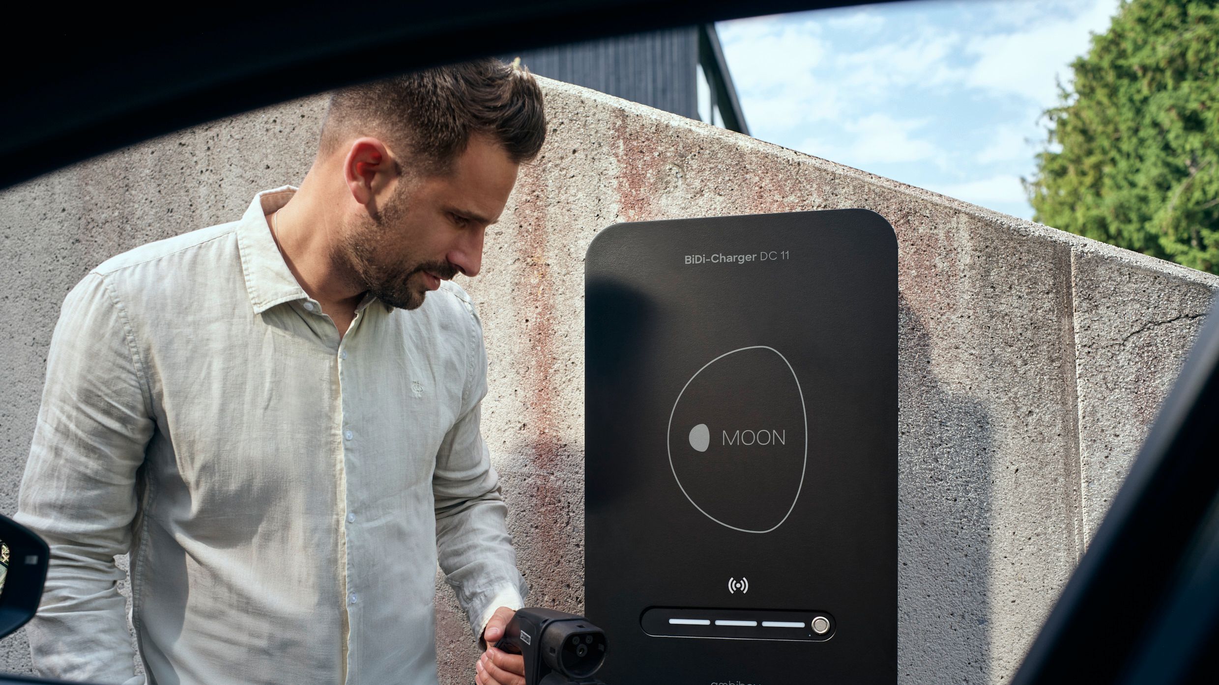 Man in front of BiDi wallbox with charging plug in hand