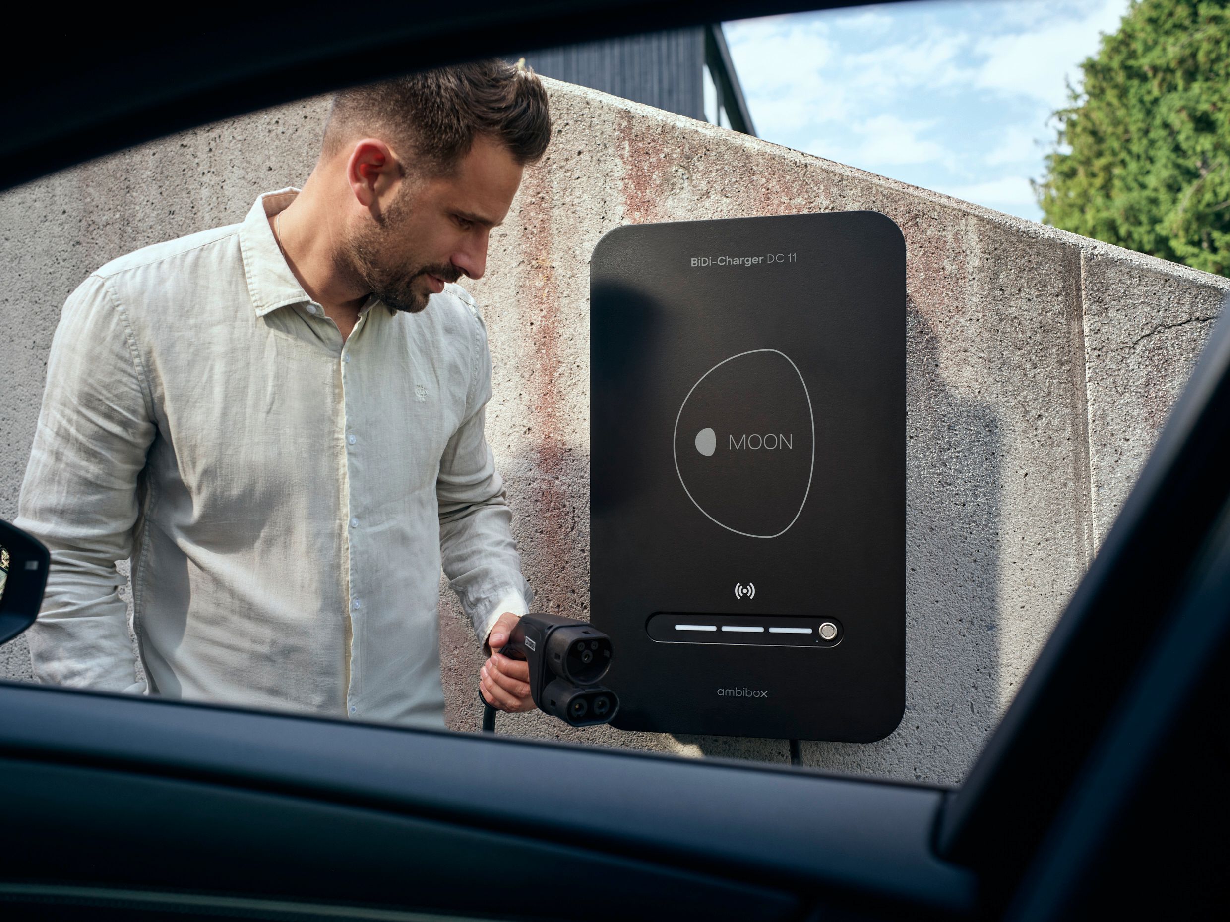 Man in front of BiDi wallbox with charging plug in hand