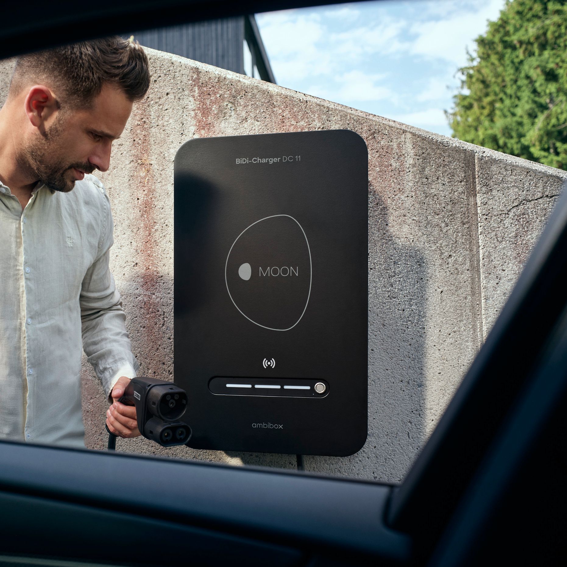 Man in front of BiDi wallbox with charging plug in hand
