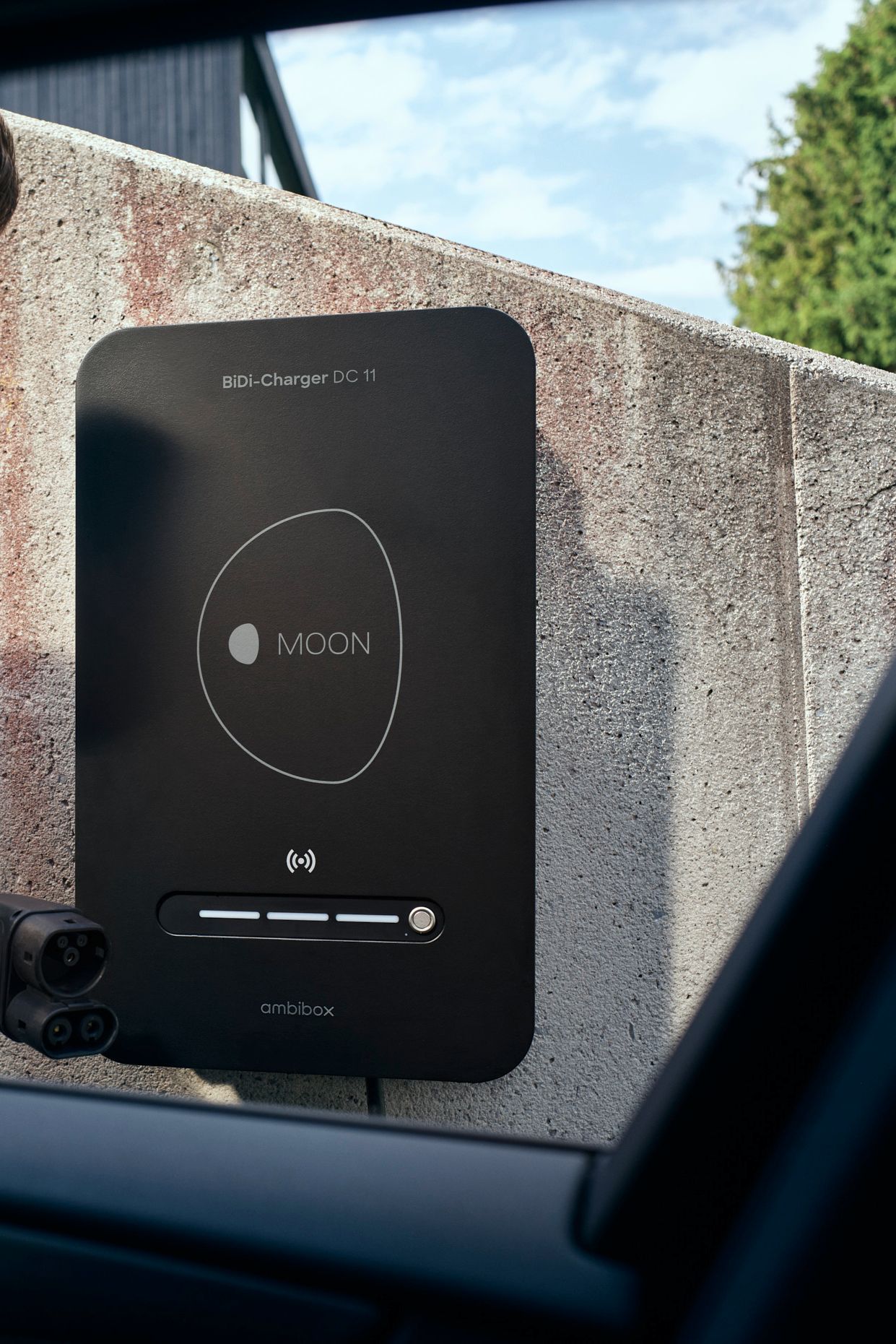 Man in front of BiDi wallbox with charging plug in hand