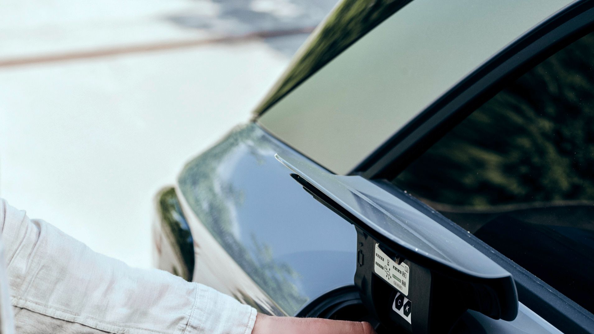 Mann steckt Kabel an E-Auto an