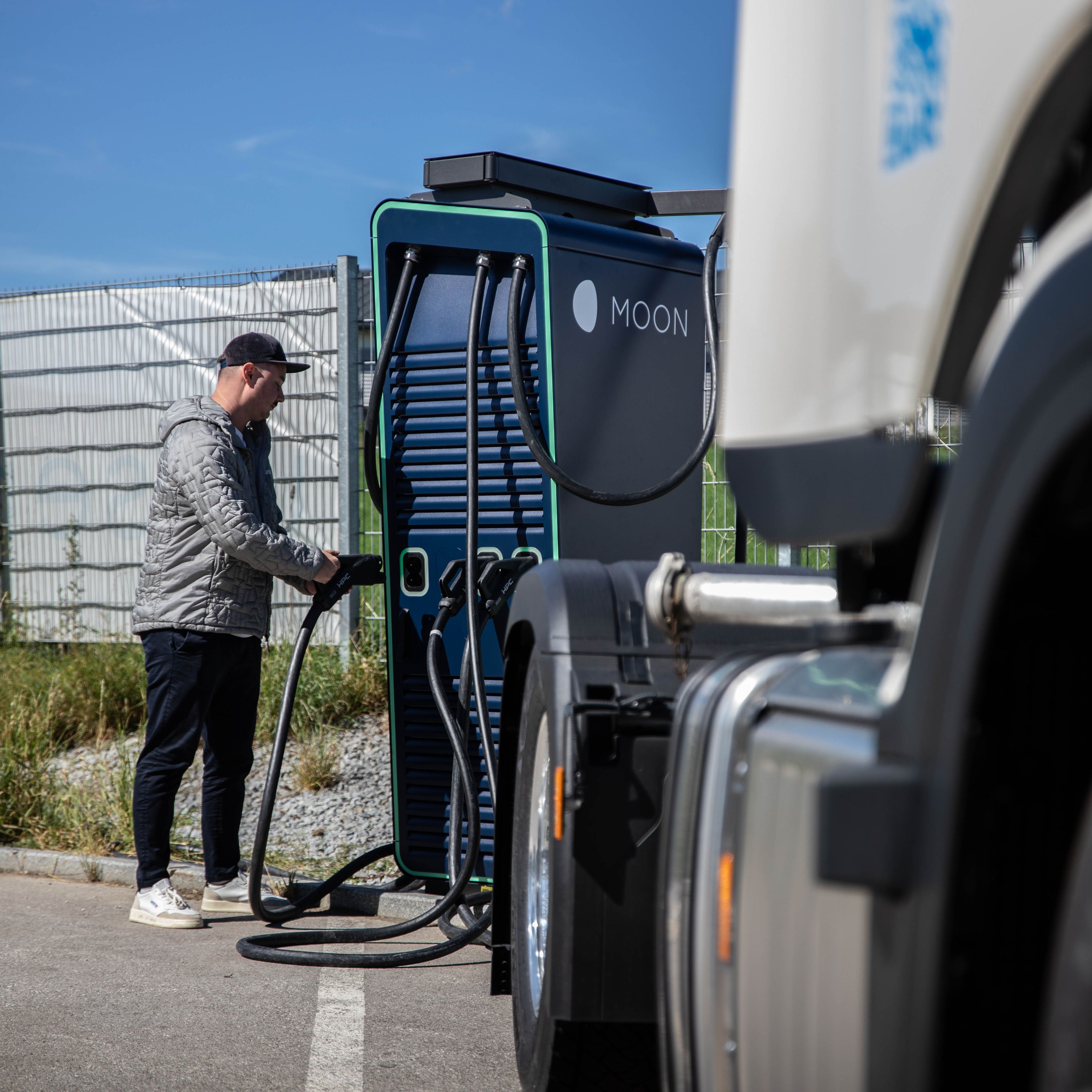 A man holds the plug of a HYC 200-400 fast charging station behind a truck