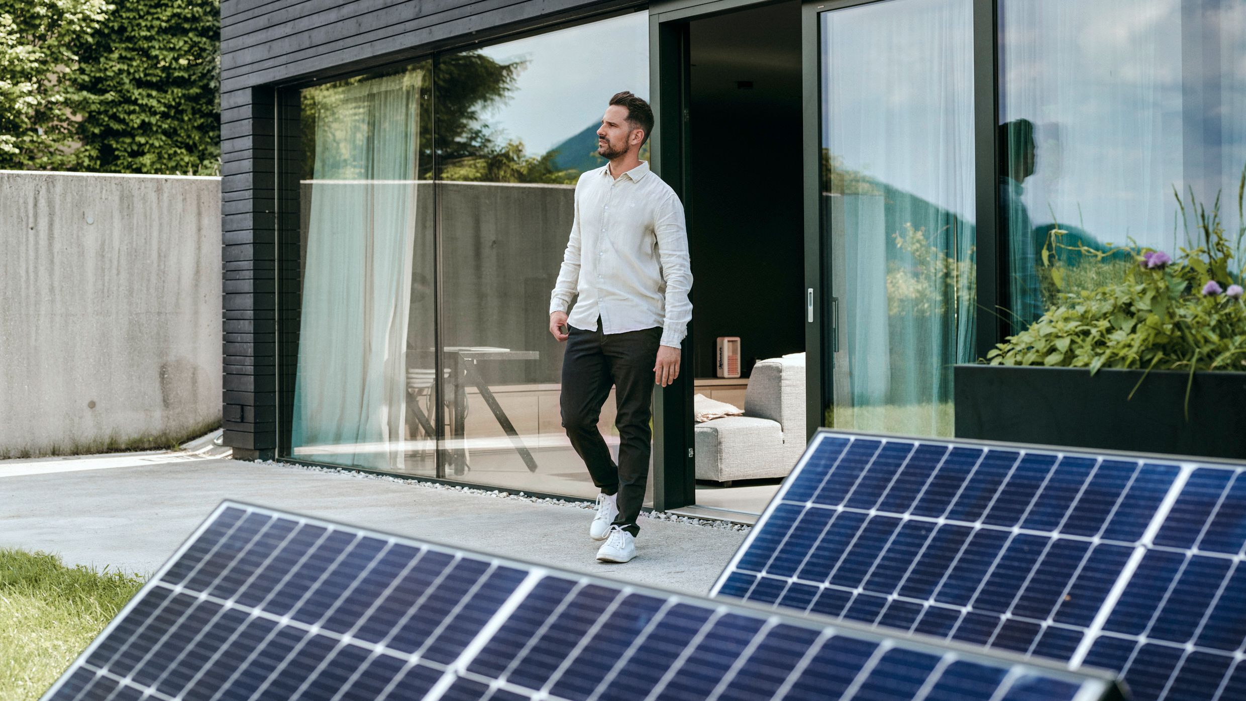 Mann vor Haus mit PV-Anlage im Vordergrund