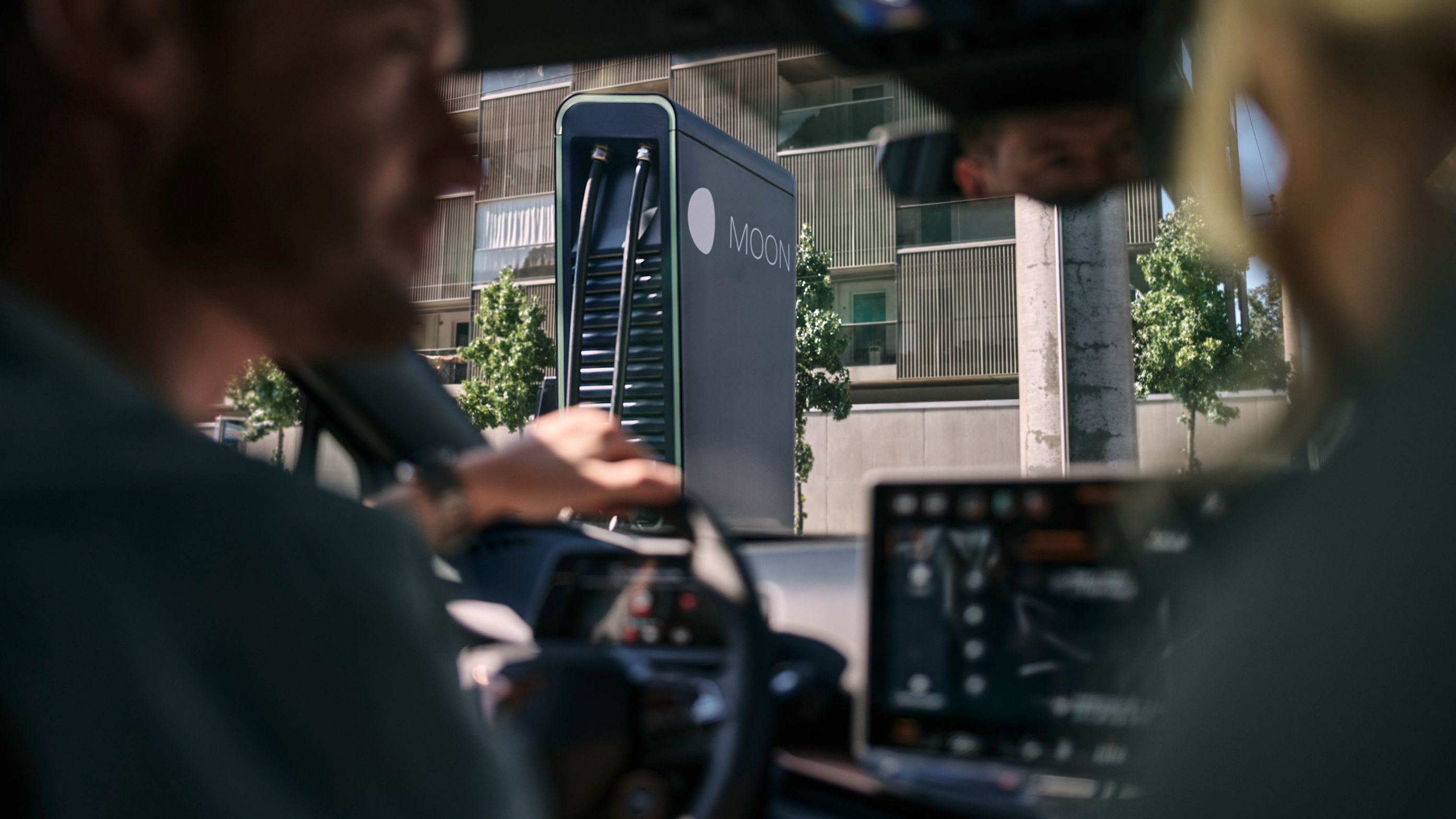 two people in an electric car in front of a fast charging station