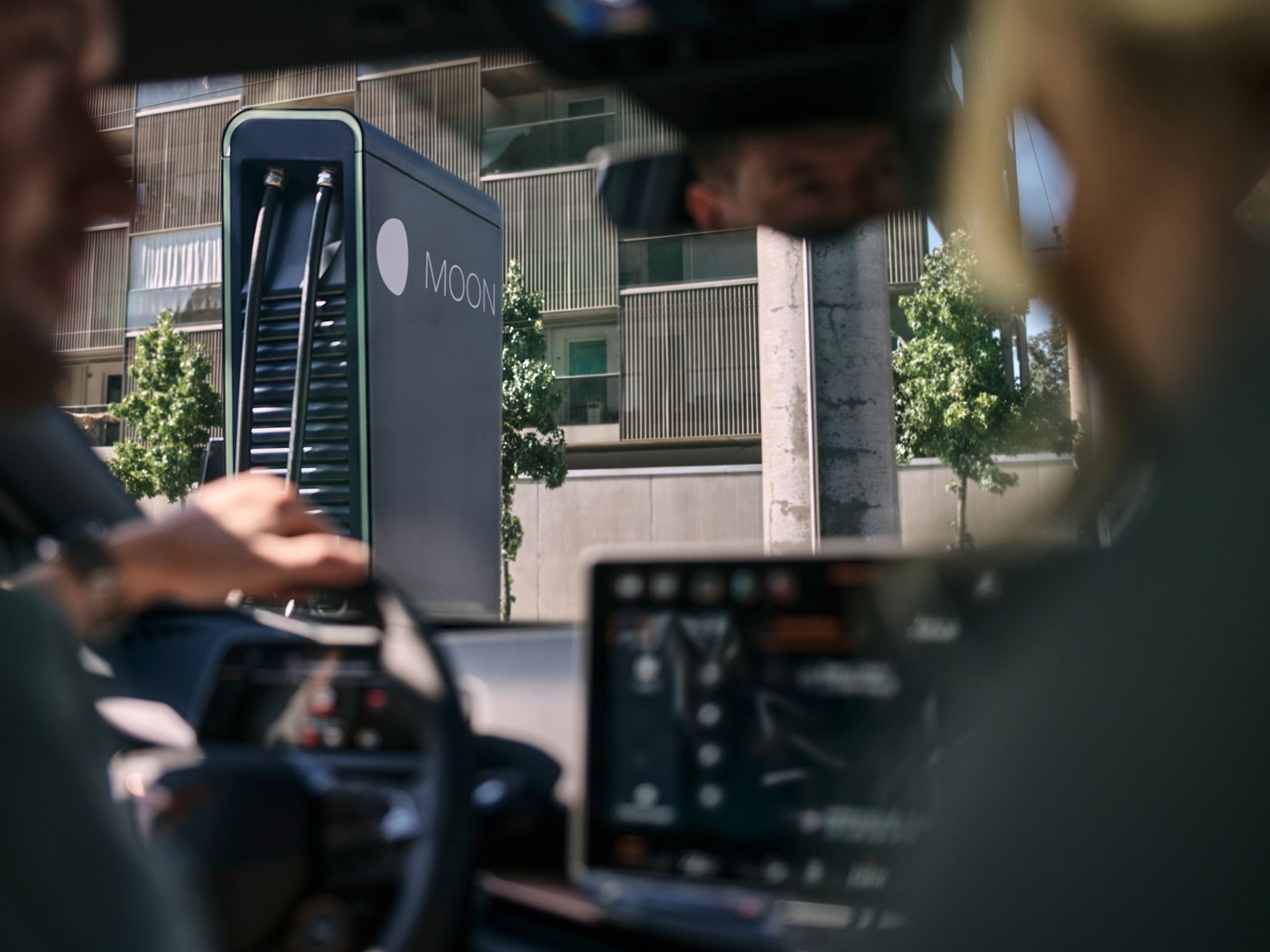 two people in an electric car in front of a fast charging station