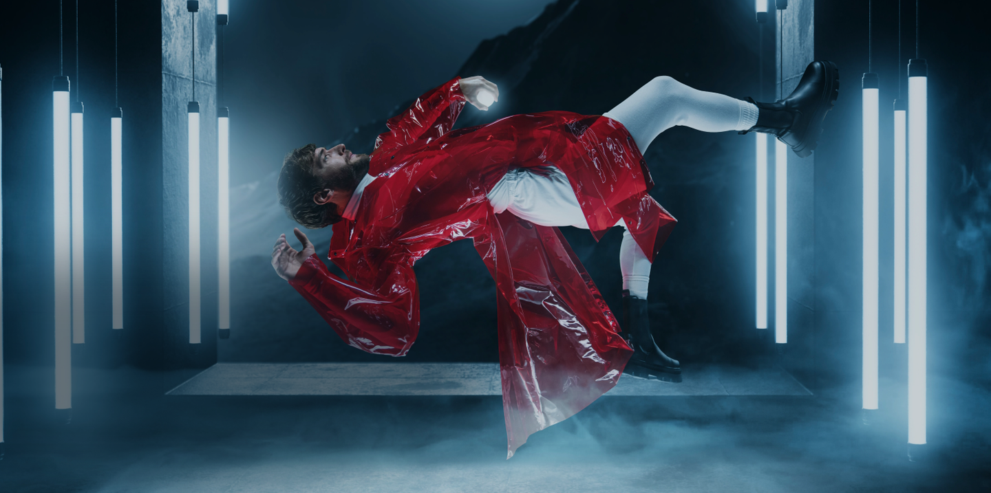 Man in zero-gravity, dressed in red trench and surrounded by lights
