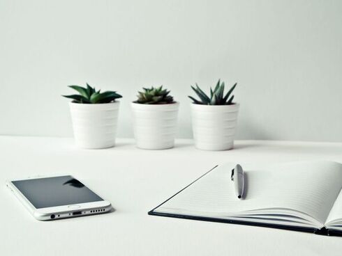Office tamble with 3 cactus plants, a notebook and a smartphone on it