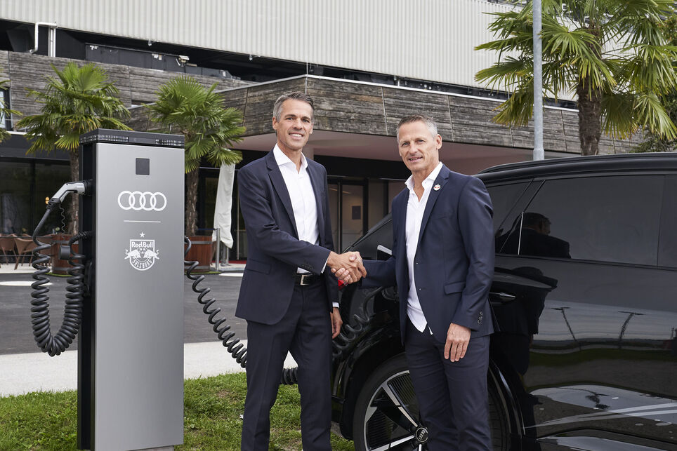 Thomas Beran and Stephan Reiter shaking hands in front of the RedBull stadiumby an Audi and MOON´s power chargers
